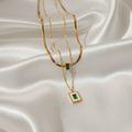 Gold necklaces with green gemstones on a satin surface
