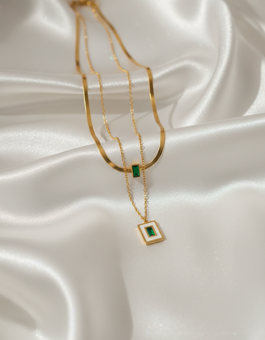 Gold necklaces with green gemstones on a satin surface