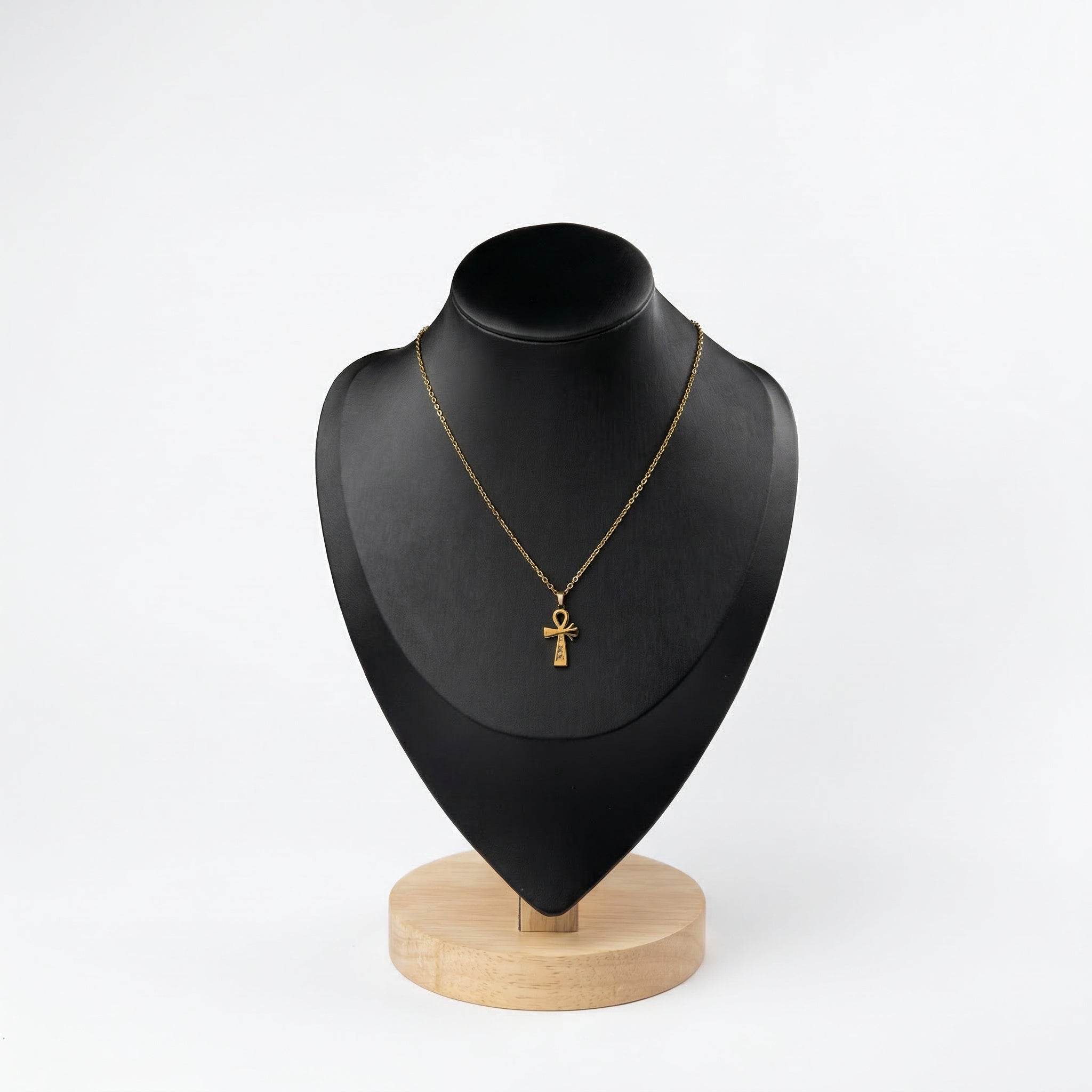 Gold Ankh necklace with crystal embellishments on a black jewelry bust