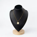 Gold rose coin necklace with white mother-of-pearl inlay and organic gold frame displayed on a black jewelry bust.