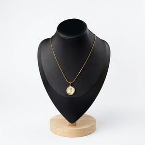 Gold rose coin necklace with white mother-of-pearl inlay and organic gold frame displayed on a black jewelry bust.